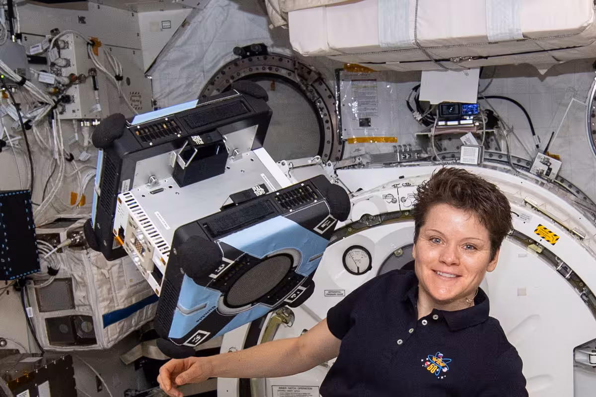 NASA astronaut Anne McClain holds Bumble, the first Astrobee free-flying robot, after unpacking it inside the Kibo module of the International Space Station