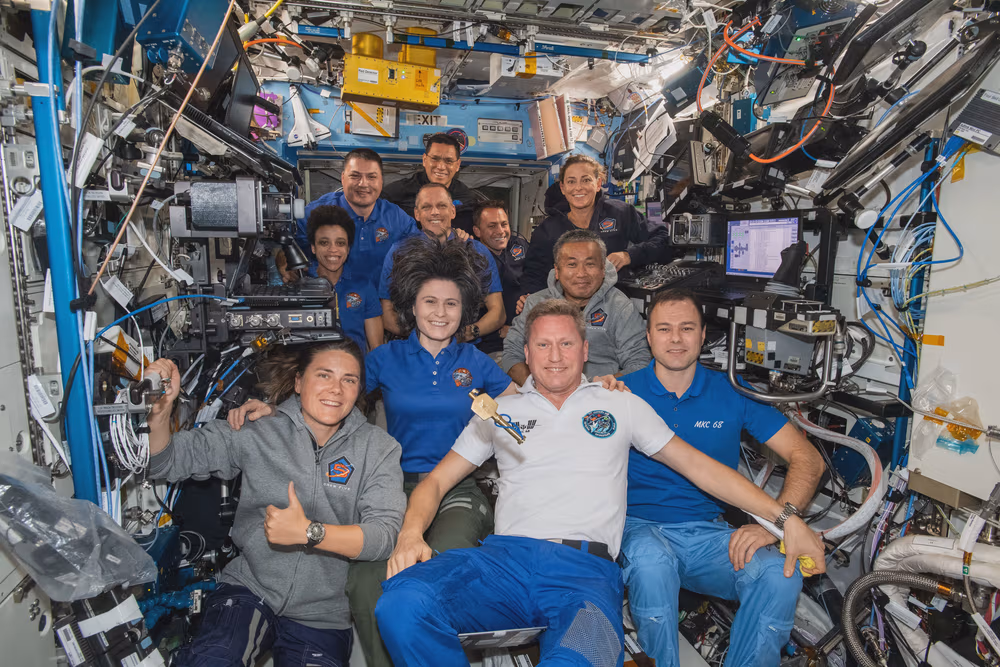 The eleven Expedition 68 crew members aboard the International Space Station pose for a portrait. In the front row from left, are cosmonauts Anna Kikina, Sergey Prokopyev, and Dmitri Petelin. In the next row, are astronauts Samantha Cristoforetti of ESA (European Space Agency) and Koichi Wakata of the Japan Aerospace Exploration Agency (JAXA). In the back, are NASA astronauts Jessica Watkins, Kjell Lindgren, Bob Hines, Frank Rubio, Josh Cassada, and Nicole Mann. A symbolic key, representing the traditional change of command ceremony, that Cristoforetti earlier handed over to Prokopyev floats in the center of the frame as he begins his spaceflight as Expedition 68 Commander.